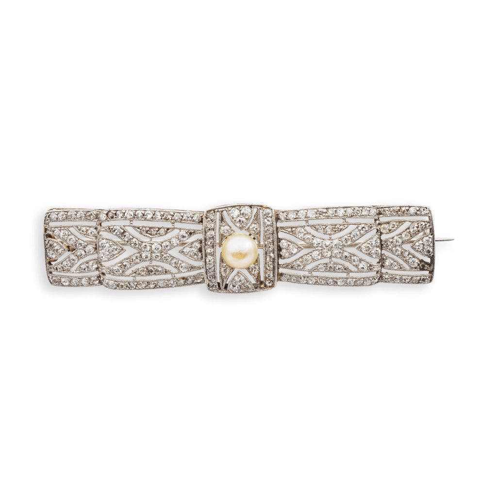 Broche des années 1925 en platine, en forme de noeud, ornée de diamants taille 8/8 en serti millegrain et d'une perle