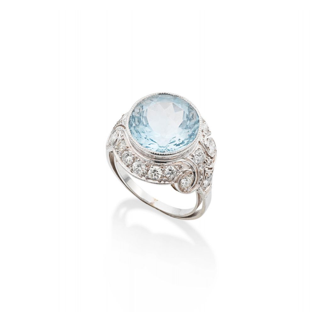 Bague en platine ornée d'une aigue-marine taille ronde en serti clos, entourée de diamants taille brillant en serti millegrain